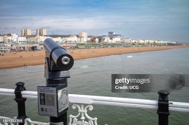 Coin operated talking telescope on Brighton Pier points towards the beach and seafront at Brighton, East Sussex, UK. The pier dates back to 1899 and...