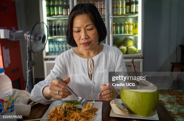 Vietnamese woman eats paad thai, a traditional Thai noodle dish in Bangkok, Thailand.