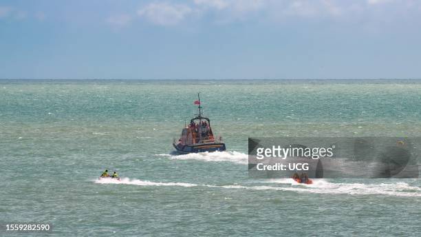 Two inflatable rescue ribs accompany Tamar class lifeboat RNLI 16-23 off the coast from Eastbourne, East Sussex, UK.