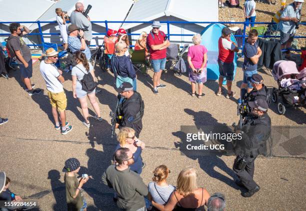 Three heavily armed Sussex Policemen walk through the crowds on Eastbourne seafront during the annual Eastbourne Airshow.