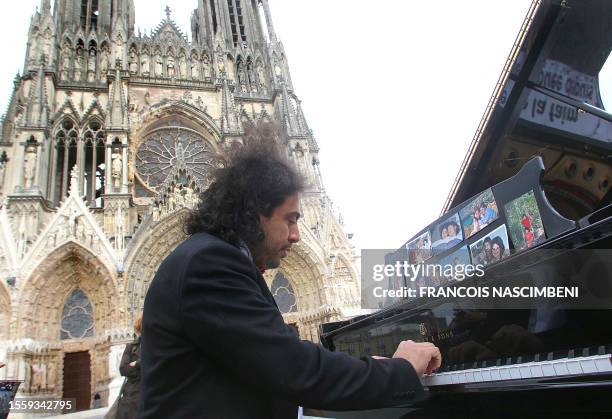 French-Lebanese musician Dominique Salloum plays the piano in front of the Reims' cathedral, on the Father's Day on June 19, 2011 in the French...