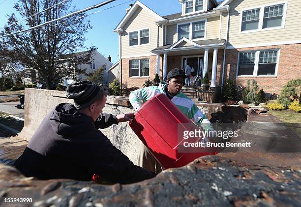 John Seridge and Karl Downie help clean out a home on Beverley Way as residents continue recovery efforts in the aftermath of Superstorm Sandy on...