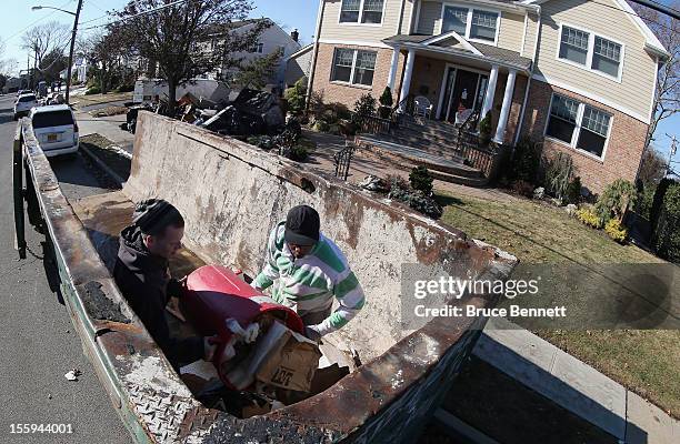 John Seridge and Karl Downie help clean out a home on Beverley Way as residents continue recovery efforts in the aftermath of Superstorm Sandy on...