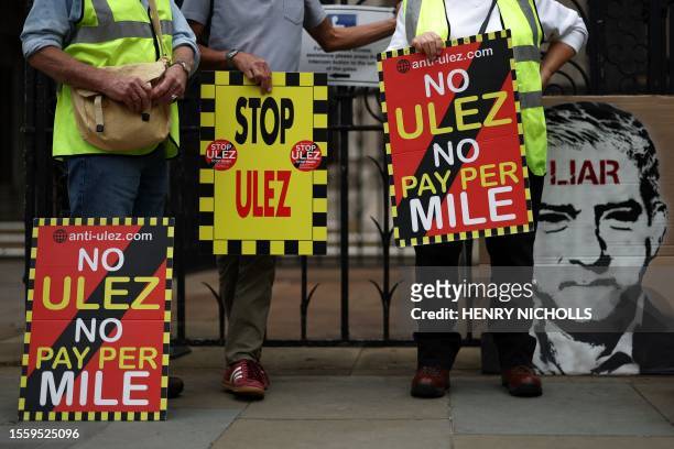 Demonstrators hold placards as they protest against the expansion of the Ultra Low Emission Zone in London, outside the Royal Courts of Justice,...