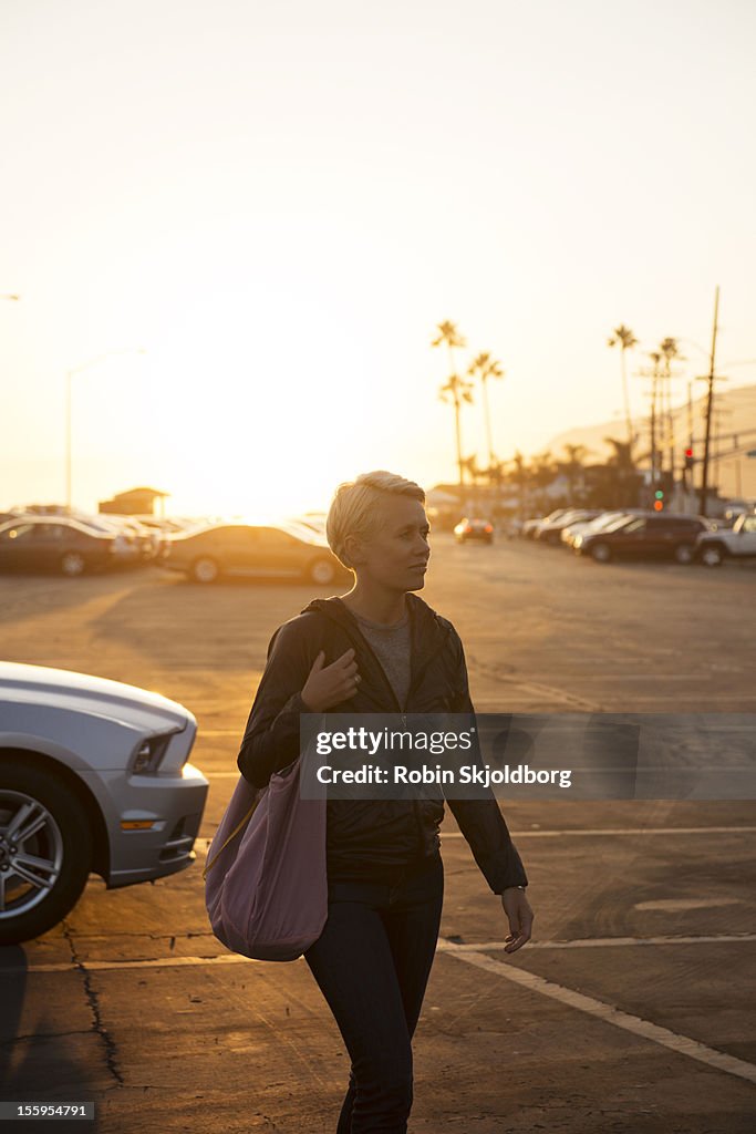 Woman walking in parking lot in sunset