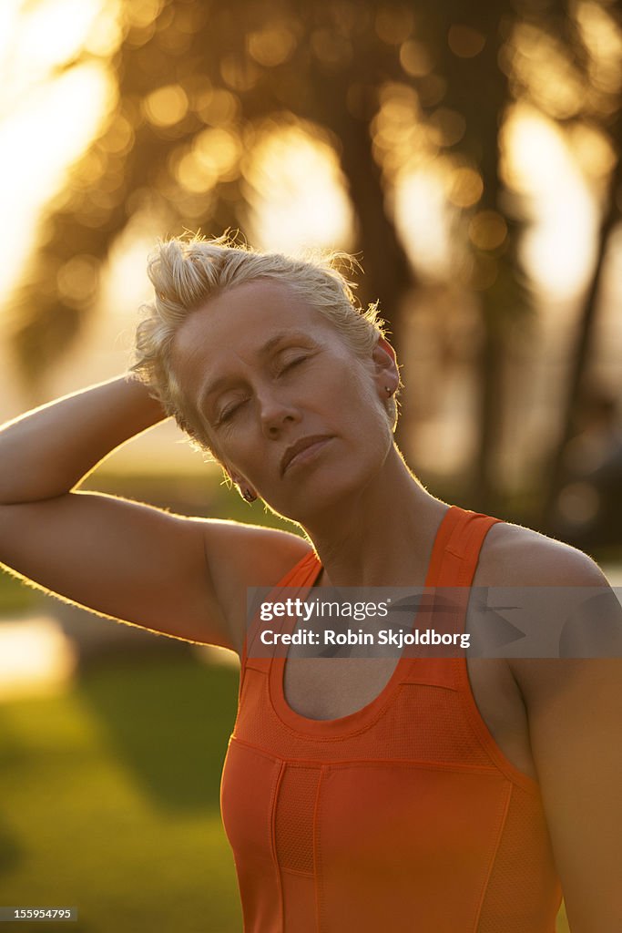 Woman in tank top stretching neck and eyes closed