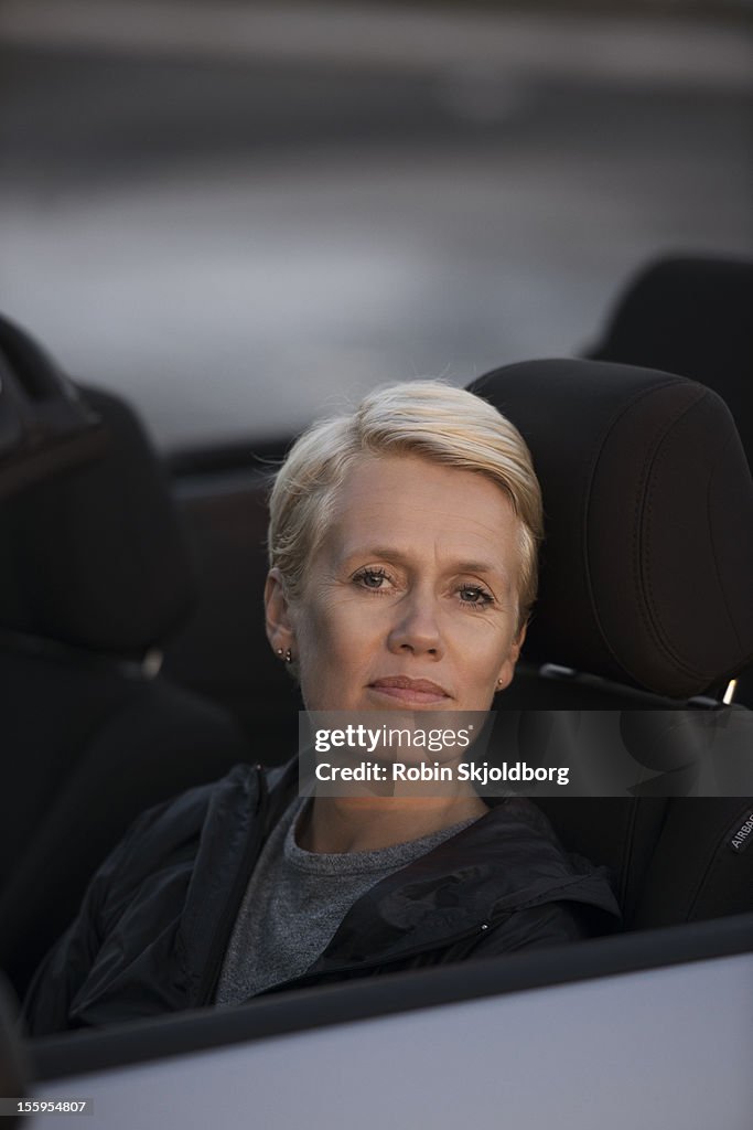 Short haired woman in convertible car smiling