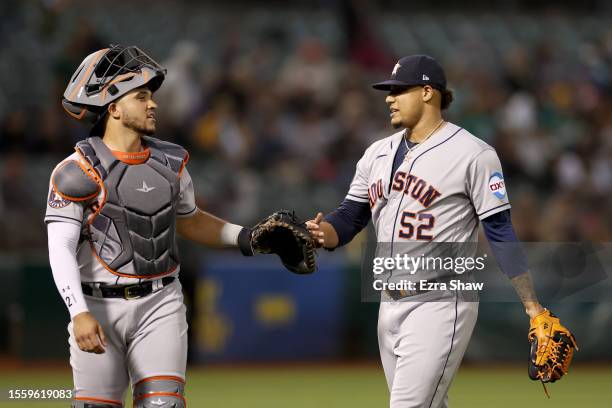 Bryan Abreu high-fives catcher Yainer Diaz of the Houston Astros at the end of the eighth inning of their game against the Oakland Athletics at...