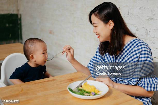 mother feeding her baby in a cafe - asian baby eating stock pictures, royalty-free photos & images