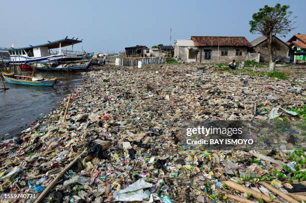 Fishermen prepare their boat for fishing next to a dirty beach with plastic waste, at Tanjung Pasir beach, in Tangerang, July 28, 2023.