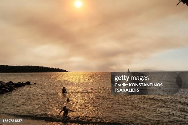 People enjoy their vacations in Milina, south Pelion as thick smoke from the wildfire in Nea Anchialos cover the sky, Greece on July 27, 2023.