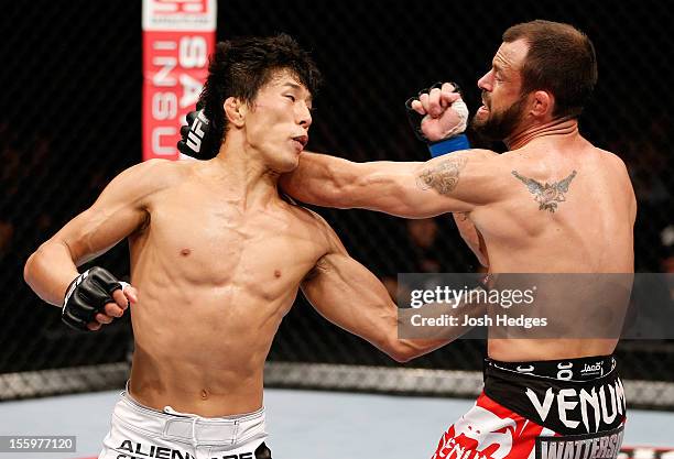 Takeya Mizugaki punches Jeff Hougland during their bantamweight bout at the UFC Macao event inside CotaiArena on November 10, 2012 in Macau, Macau.