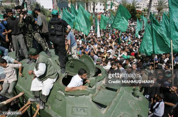 Hamas militants parade on an armoured vehicle belonging to the Fatah-linked Presidential Guard Force 17 exhibited as a war trophy among a crowd of...