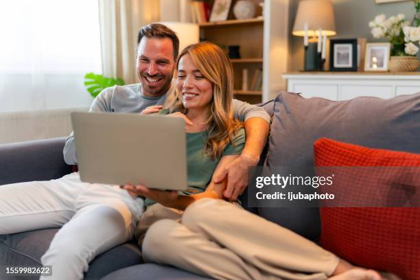 couple sitting in their living room and checking their finances using laptop - laptop home stock pictures, royalty-free photos & images