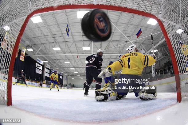 Hudson Fasching of the USA looks over his shoulder as teammate Evan Allen scores a first period goal against Ebbe Sionas of Sweden during the U-18...