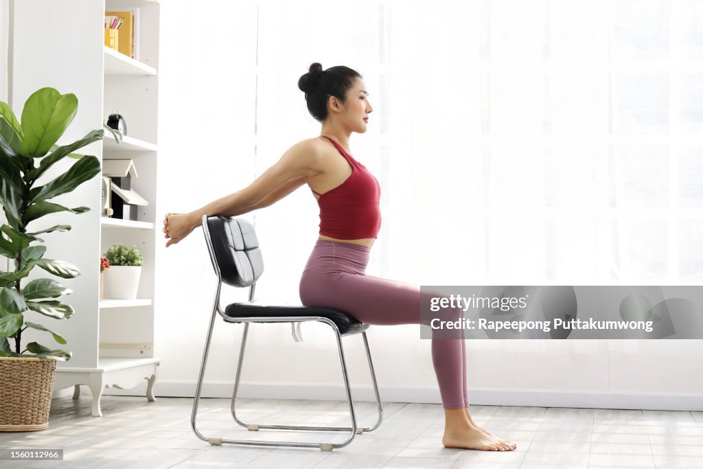Young woman wearing sports clothes and exercising at work using the chair. Stretching to treat office syndrome