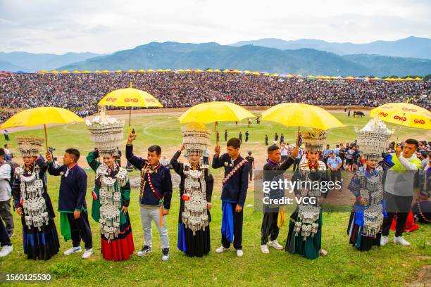 People wearing traditional clothing with umbrellas in their hands wait for a beauty contest during the Torch Festival on July 19, 2023 in Liangshan...