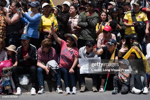 Parade-viewers hold Colombian flags and the national team t-shirt during the military parade for the 213 years of Colombia's independence, in Bogota,...