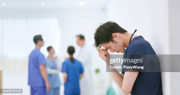 depressed male nurse in hospital - harassment work stock pictures, royalty-free photos & images