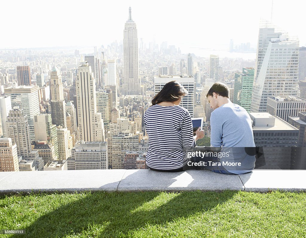 Man and woman using digital tablet in city