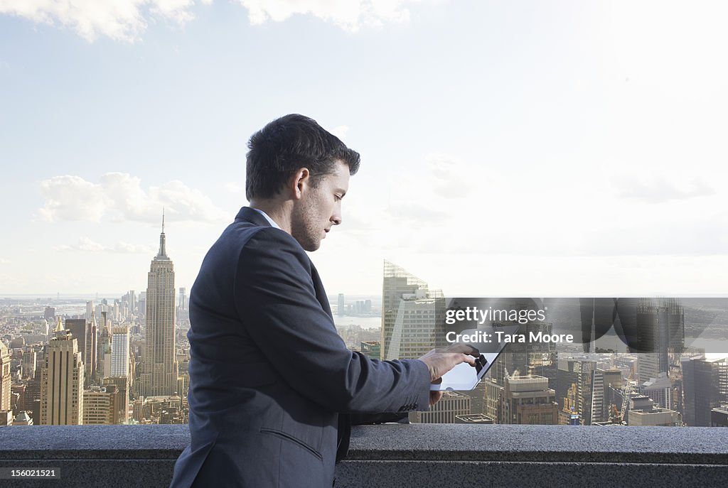 Business man using digital tablet next to city sky