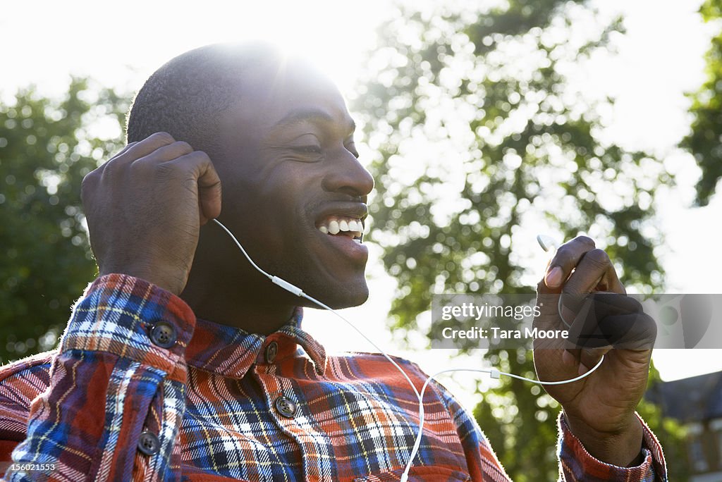Man smiling in park putting in ear phones