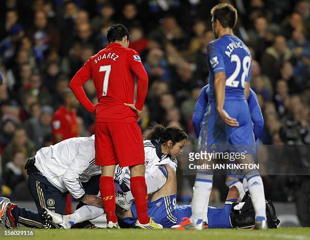 Liverpool's Uruguayan striker Luis Suarez checks on Chelsea's English defender John Terry as he is attended to by club physio Eva Carneiro after...