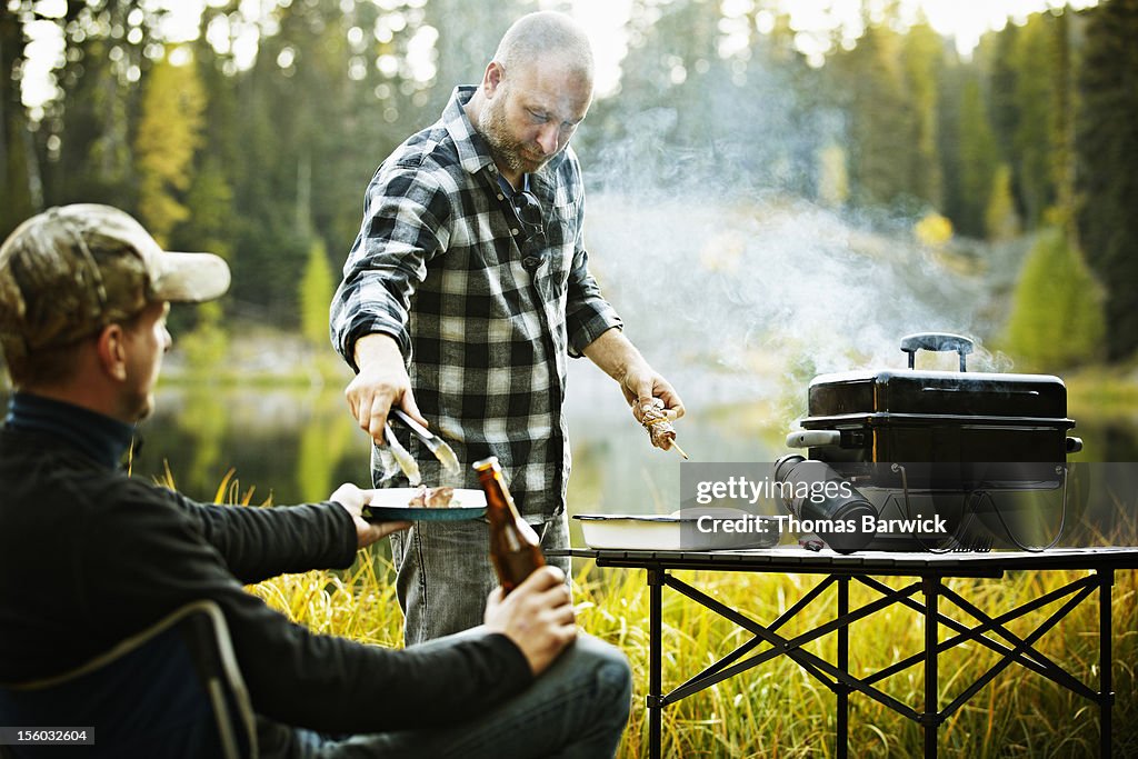 Man serving friend from outdoor barbecue