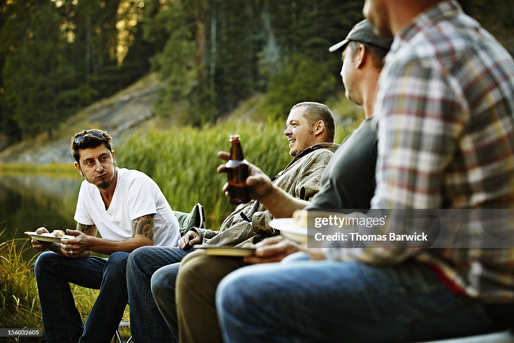 Group of friends eating and drinking while camping