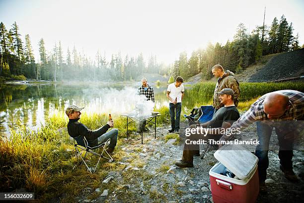 group of friends barbecuing next to mountain lake - men friends beer outside stock-fotos und bilder