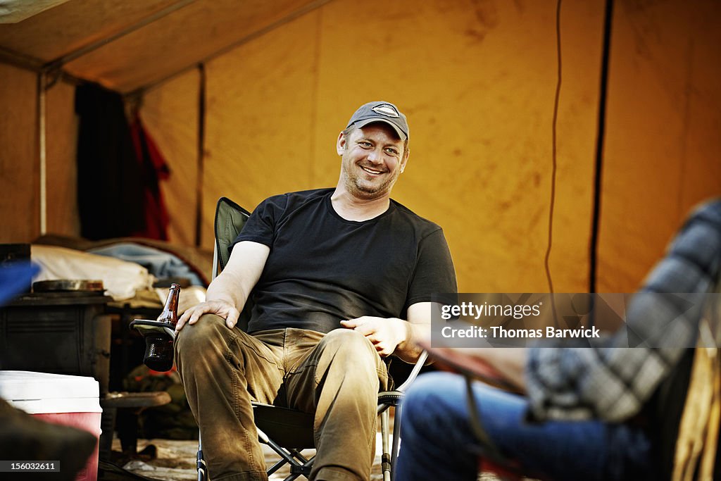 Smiling man sitting in hunting camp with friends