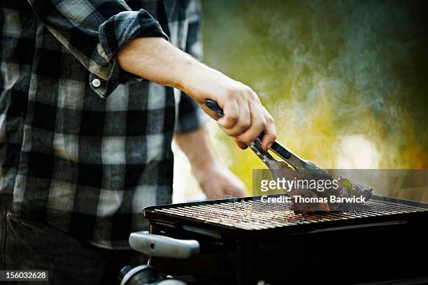 man holding tongs barbecuing kebab on grill - tang stockfoto's en -beelden