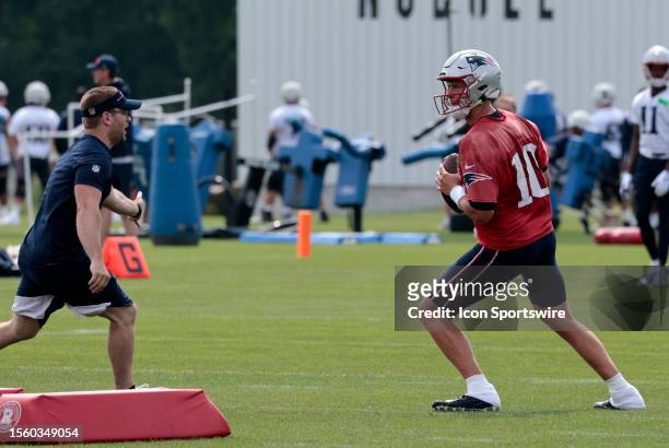 New England Patriots assistant quarterbacks coach Evan Rothstein distracts quarterback Mac Jones during New England Patriots Training Camp on July 27...