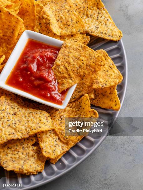 nachos-chips, maischips in schüssel, tortilla-chips, kartoffelchips, chips, maischips-nachos und dip-sauce, mexikanische nachos oder tortilla-chips in einer schüssel mit chili-salsa-sauce getaucht - tortilla chip stock-fotos und bilder