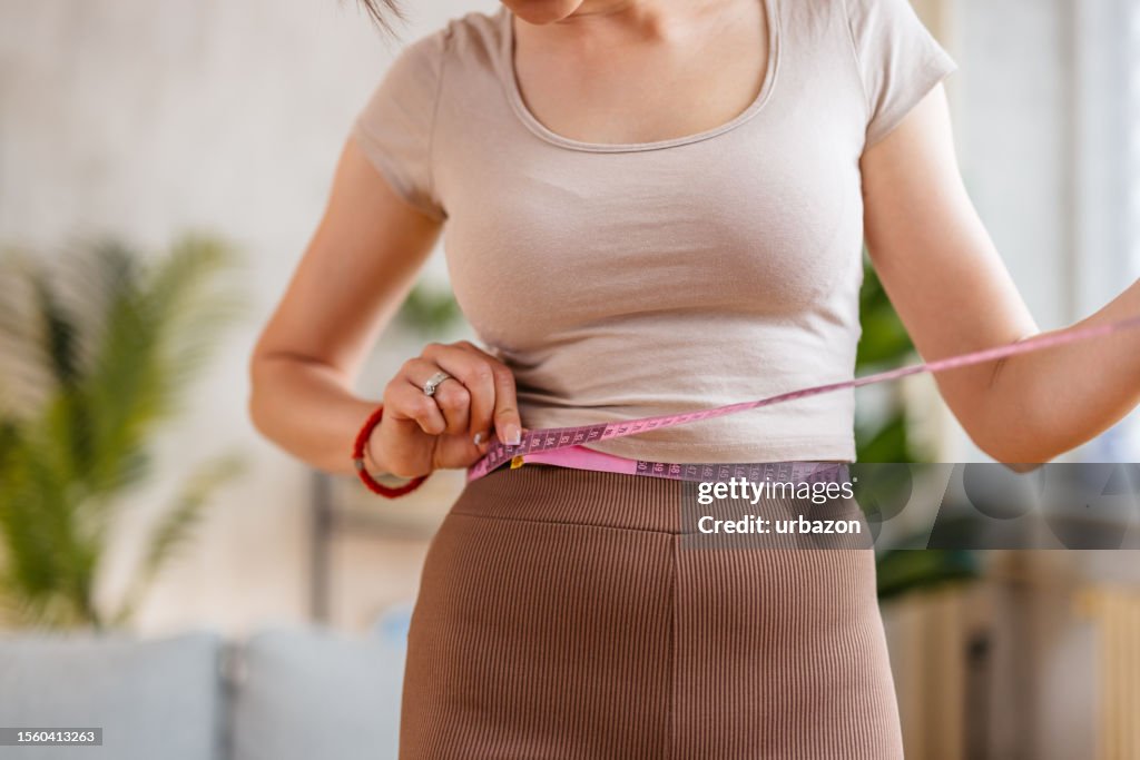 家で腰を測る若い女性