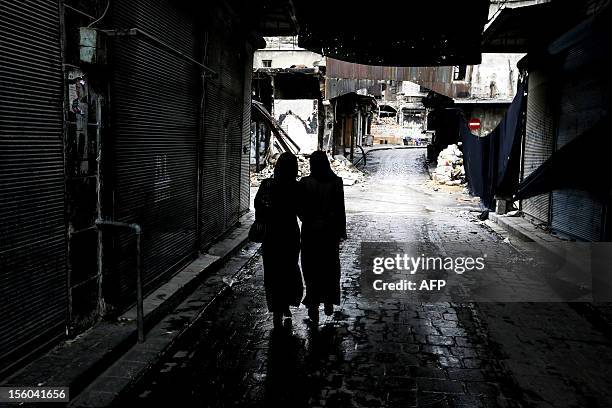 Syrian women walk down a souk shielded from the rain in Syria's northern city of Aleppo on November 11, 2012. As the winter weather takes hold, the...