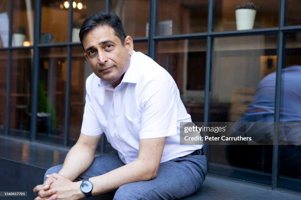 A mature businessman sitting outside a modern building