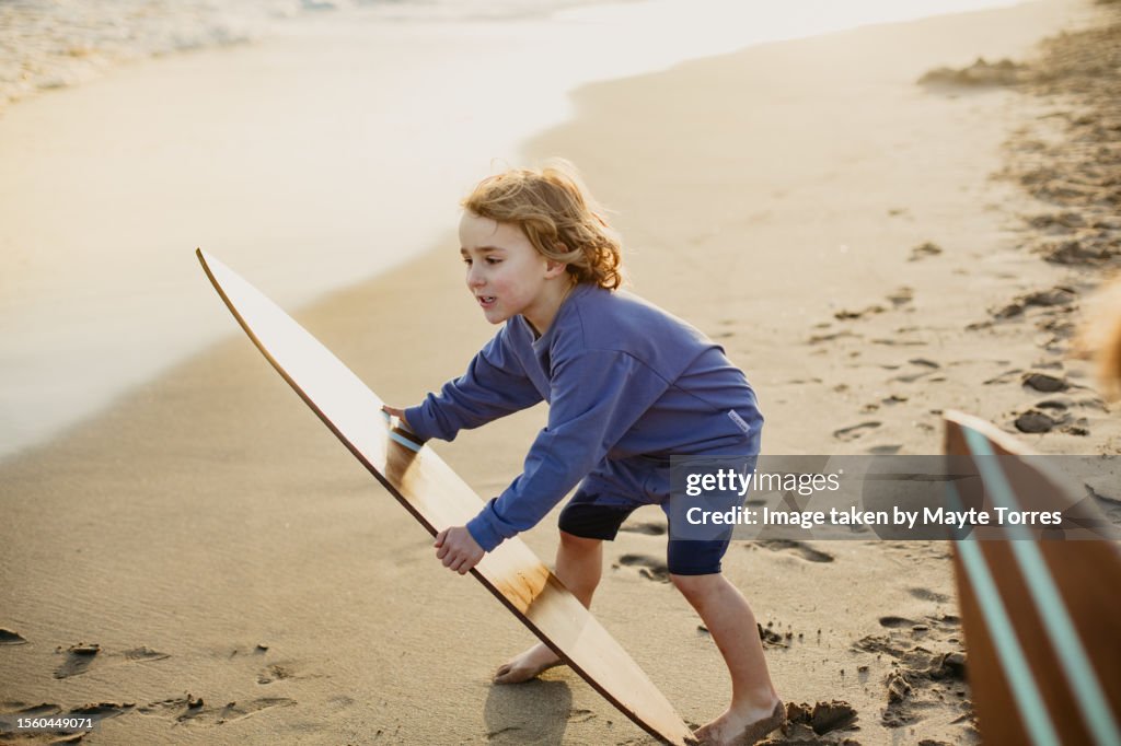Boy putting a surfboard in the water
