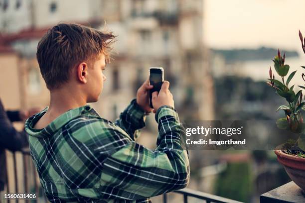 teenage boy filming the beautiful view in the charming town of tropea - teen doing filming imagens e fotografias de stock