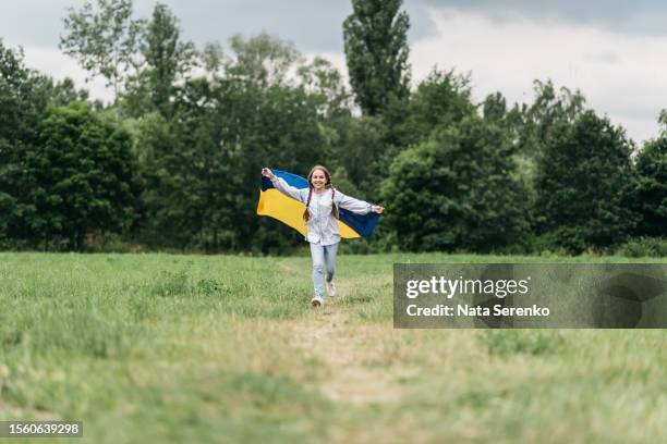 ukrainian child girl in embroidered shirt vyshyvanka with yellow and blue flag of ukraine in garden - maidan nezalezhnosti stock pictures, royalty-free photos & images