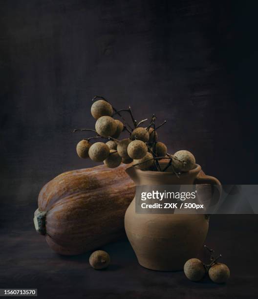 close-up of pumpkin and fruits in jar on table against black background,china - longan stock-fotos und bilder
