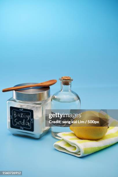 close-up of baking soda lemon and vinegar against blue background - aceto foto e immagini stock