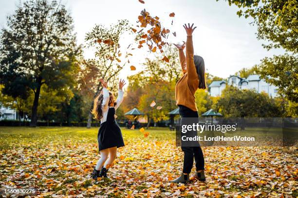 mother and daughter throwing autumn leaves in the air - fallen lord stock pictures, royalty-free photos & images