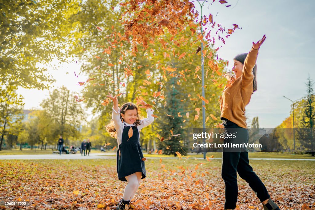 Mother and daughter throwing autumn leaves in the air