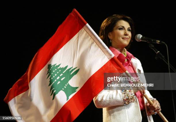 Lebanese singer Magida al-Roumi holds a national flag during her performance in downtown Beirut's landmark Martyrs Square, late 13 April 2005, as...