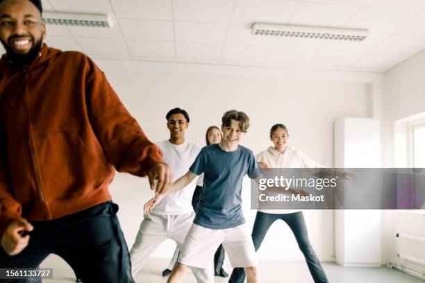 smiling boy learning to dance with friends and teacher in studio at high school - dance studio stock pictures, royalty-free photos & images