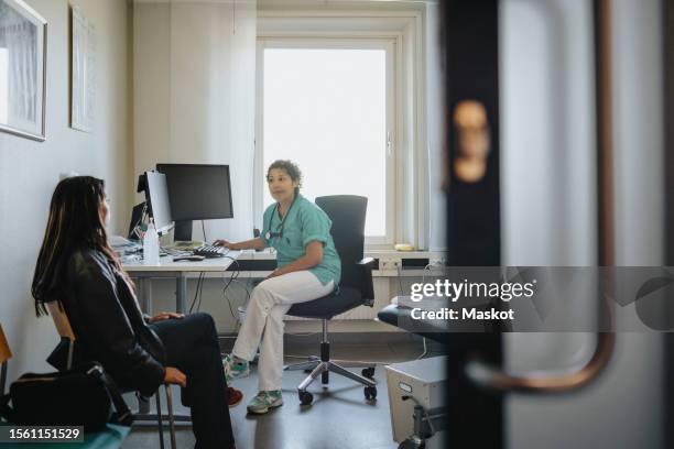 female physician discussing with young woman in clinic - médico de cabecera fotografías e imágenes de stock