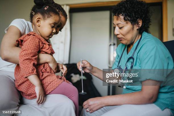 female doctor with reflex hammer examining girl in clinic - martelo de reflexo - fotografias e filmes do acervo