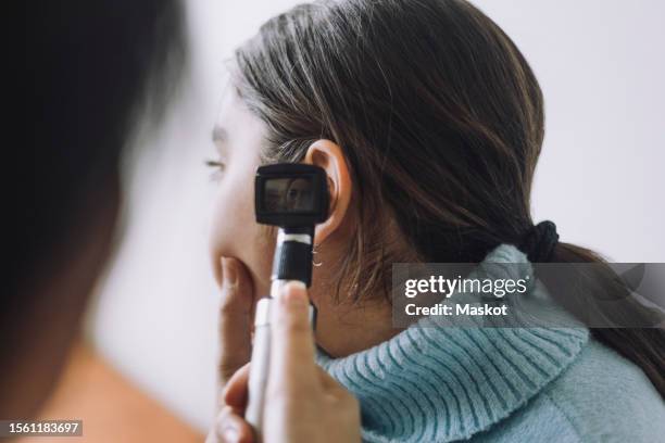 doctor examining patient's ear using otoscope at hospital - oreja fotografías e imágenes de stock