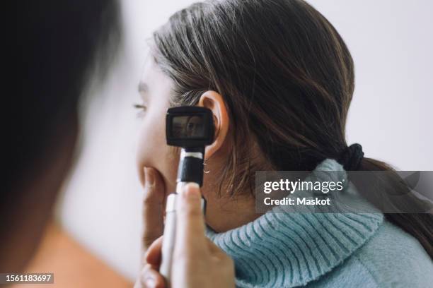 doctor examining patient's ear using otoscope at hospital - otoscope stockfoto's en -beelden